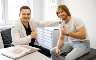 Pacjent pokazuje kciuk w górę, siedząc obok dobrego urologa w gabinecie.