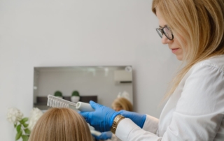 Trycholog przeprowadza zabieg na włosach pacjenta.