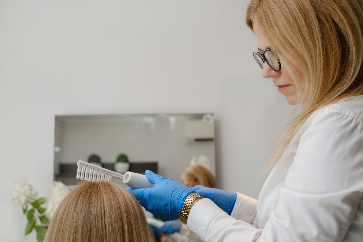 Trycholog przeprowadza zabieg na włosach pacjenta.
