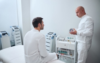 Mężczyzna w białym fartuchu rozmawia z pacjentem w poradni urologicznej.