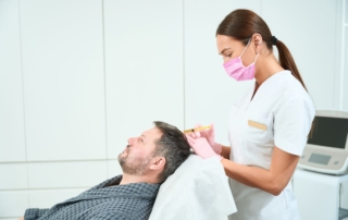 Trycholog wykonuje zabieg na skórze głowy pacjenta.