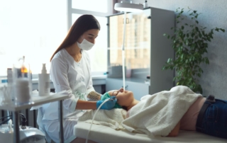 Lekarz medycyny estetycznej wykonuje zabieg na twarzy pacjentki.