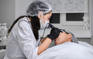 Specjalistka wykonuje zabieg związany z dermatologią estetyczną na twarzy pacjentki.