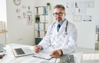 W gabinecie siedzi dobry urolog z dokumentacją medyczną.
