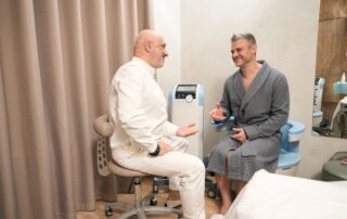 Pacjent w szlafroku rozmawia z lekarzem o badaniach kontrolnych w gabinecie urologicznym
