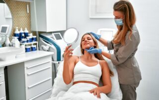 Pacjentka z lusterkiem rozmawia ze specjalistką o wyborze kliniki medycyny estetycznej podczas konsultacji